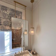 a bathroom with a sink, mirror and light fixture hanging from it's ceiling