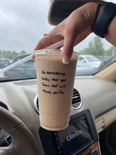 a woman is holding a coffee cup in her hand while she sits in the driver's seat