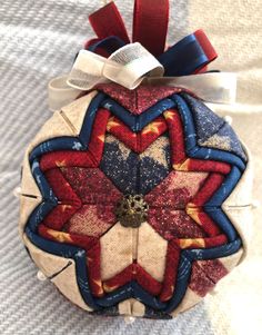 a red, white and blue ornament hanging from a ribbon on a bed