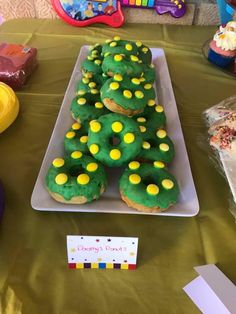 a table topped with lots of cupcakes covered in green and yellow frosting