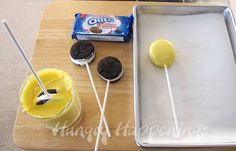 an ice cream sundae with oreo cookies on it and two lollipops