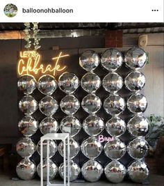 there is a large display of shiny balls on the wall with neon lights above it