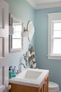 a white sink sitting under a mirror in a bathroom next to a toilet and window