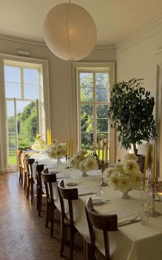 a dining room table set with white flowers and place settings for four people to sit at