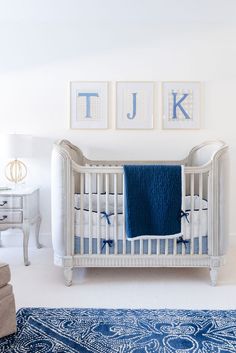 a white crib with blue blankets on it and two pictures above the crib