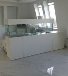 an empty room with white cabinets and glass counter tops in the center is a bed