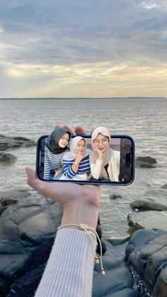 a person taking a selfie with their cell phone near the water's edge