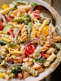 a bowl filled with pasta salad on top of a wooden table