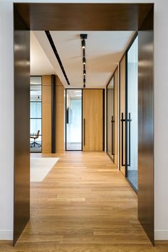 an empty hallway with wooden floors and glass doors