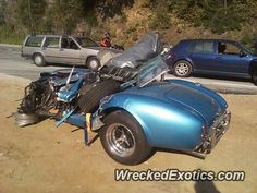 an old blue car is parked on the side of the road with it's hood up