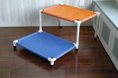 a blue and orange cart sitting on top of a wooden floor next to a window