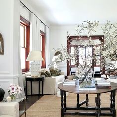 a living room filled with furniture and flowers on top of a coffee table in front of a window