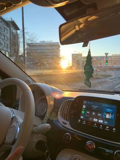 the sun is setting behind a car driving down the street in front of some buildings