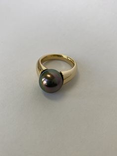 This is a near perfect pearl with no blemish. This large black pearl from the south sea shines with many colorful hues. Over the black undertone one can see green, pink, blue, and many more colors. The high quality pearl has great levels of nacre and is set on a wonderful Gold band. The ring is size 7 1/2 and weighs 15.08 grams.  Edmund Weber Jewelers has been creating custom jewelry in San Francisco from 1962. Now, three generations of Weber jewelers are dedicated to bringing customers wonderfu Black Pearl Ring, Pearl Wedding Ring, Yellow Diamond Rings, Pearl Jewellery, Silver Wedding Rings, South Seas, Gold Diamond Rings, Yellow Diamond, Black Pearl