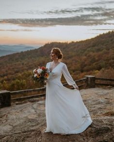 a woman standing on top of a mountain holding a bouquet