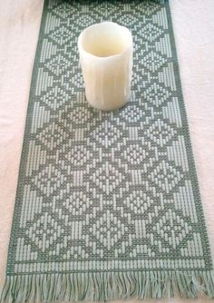 a white candle sitting on top of a table next to a green and white rug