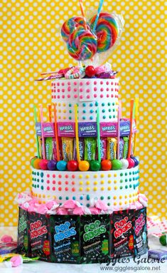 a multi - tiered cake with candies and lollipops on top