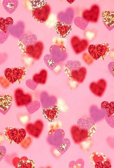 many hearts on a pink background with glitter in the shape of small red and pink hearts