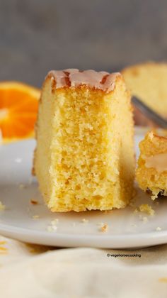 a piece of cake on a plate with an orange in the background