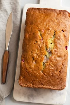 a loaf of fruit cake on a cutting board next to a knife