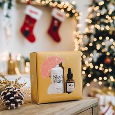 an open gift box sitting on top of a wooden table next to a christmas tree