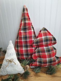 three plaid christmas trees sitting on top of a wooden floor