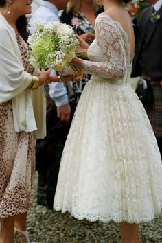 two women in wedding dresses are touching each other's hands while others look on