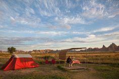 a person sitting at a table next to a tent in the middle of a field