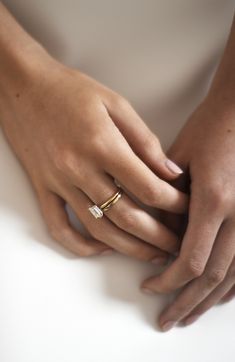 two hands holding each other with their wedding rings on top of one hand and the other