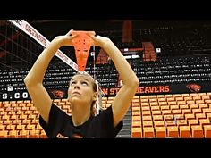 a woman is playing basketball in an orange and black arena with empty bleachers