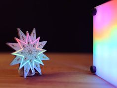 a paper snowflake sitting on top of a wooden table next to a colored object