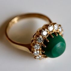 This Tudor design features 0.83 carats of diamonds encircling a malachite cabochon. Available in sizes 5-8. Elegant Green Cabochons For Formal Occasion, Green Gemstone Cabochons For Formal Use, Elegant Green Cabochon Emerald Ring, Elegant Green Emerald Cabochon Ring, Fine Jewelry Green Cabochons For Formal Occasions, Green Cabochons For Formal Fine Jewelry, Green Gemstone Cabochons Fine Jewelry, Elegant Green Gemstone Cabochons, Elegant Green Dome Ring