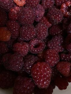 a bowl filled with raspberries and oranges on top of a white table