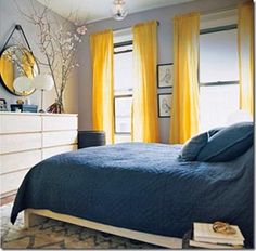 a bedroom with yellow curtains and blue bedding