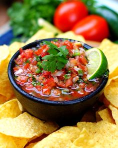 a black bowl filled with salsa surrounded by tortilla chips