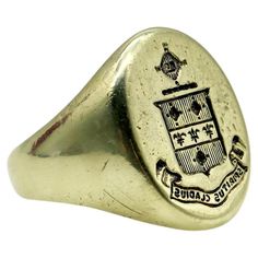 This 14k gold signet ring features a family crest of a shield topped with a radiating cross. The shield is divided into three sections, with vertical lines across the top and bottom sections, and a row of fleur-de-lis across the center. Above the shield is a cross like symbol that contains a tiny image that appears to be a book. Below the shield is a banner with the Latin phrase "Spiritus Gladius” which translates to "Sword of the Spirit.” A wonderful patina has settled into the signet’s engraving that adds depth to and delineates the images. The face of the ring measures 5/8” x 3/4” and the ring weighs 10.9 grams. Marked as 14k gold. Circa 1900, this makes a great unisex ring and could be sized up to fit a man—but we love it because the smaller ring size makes it perfect for a woman or so 14k Gold Signet Ring, Like Symbol, Latin Phrases, Vertical Lines, Gold Signet Ring, The Shield, Unisex Ring, Small Rings, Family Crest