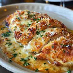 a white plate topped with chicken covered in gravy and parmesan cheese