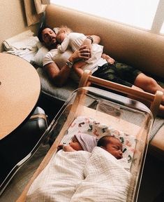 a man laying on top of a couch next to a baby in a crib