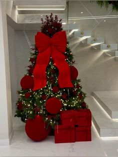 a decorated christmas tree with red balls and bows on it's top in a white room