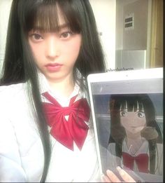 a girl with long black hair holding up a laptop