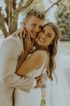 a bride and groom embracing each other in front of trees