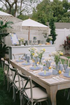 an outdoor table set up with blue and white plates, vases and flowers on it