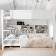 a white bunk bed sitting in a bedroom next to a book shelf filled with books