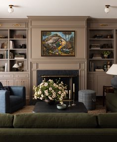 a living room filled with furniture and a painting on the wall over a fire place