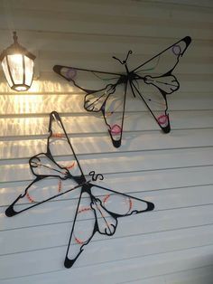 three metal butterflies hanging from the side of a house