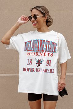 Whether you're cheering on your team from the sidelines or enjoying the festivities at the tailgate, our Delaware State Hornets Unity Oversized Crewneck Teeis sure to keep you looking and feeling fabulous all season long. Join the fashion game and make every game day unforgettable! White Sports Fan College Top, University Logo Tops For Sports Events, University Logo Short Sleeve Top For Sports Season, University Logo Sports Fan Tops, University Logo Tops For Fan Gear, White Varsity Sports Fan Top, Game Day Sports Fan Crew Neck Top, Collegiate Tops With University Logo, Sporty University Logo Tops For Game Day