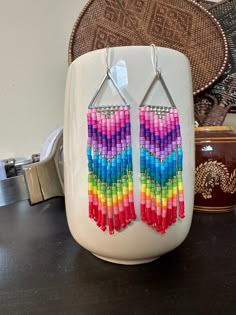 a pair of earrings made out of multicolored beads sitting on top of a table