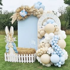 a bunch of balloons that are in the grass near a box and some bunny decorations