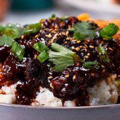 a bowl filled with rice covered in sauce and garnished with cilantro