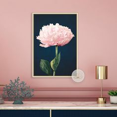 a large pink flower is on the wall above a table with a vase and potted plant